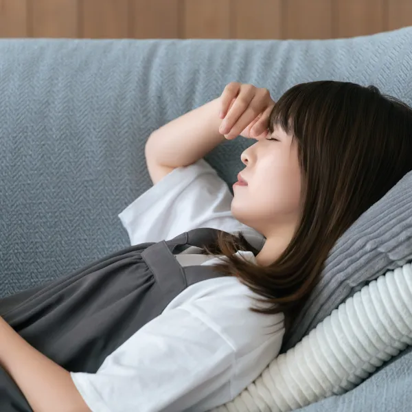 体調がすぐれずソファで休む女性